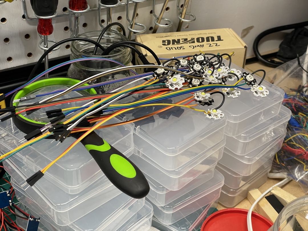 Neatly organized multicolored wires and LED modules on top of clear plastic storage boxes.